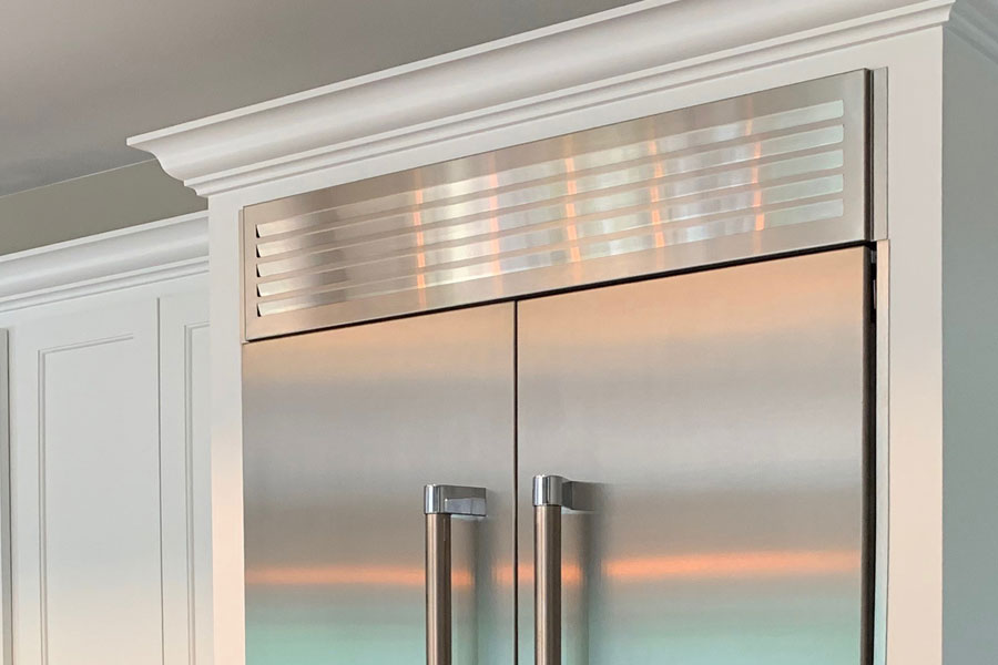 Fridge top vent by Micro-Trim installed above a stainless steel.